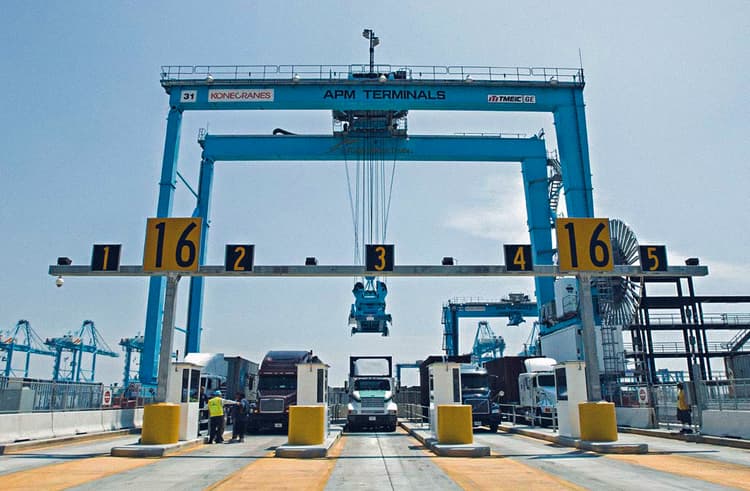 APM Terminals gate with trucks ready for container handling, showcasing efficient logistics and coordination under the management of large cranes for streamlined port operations.