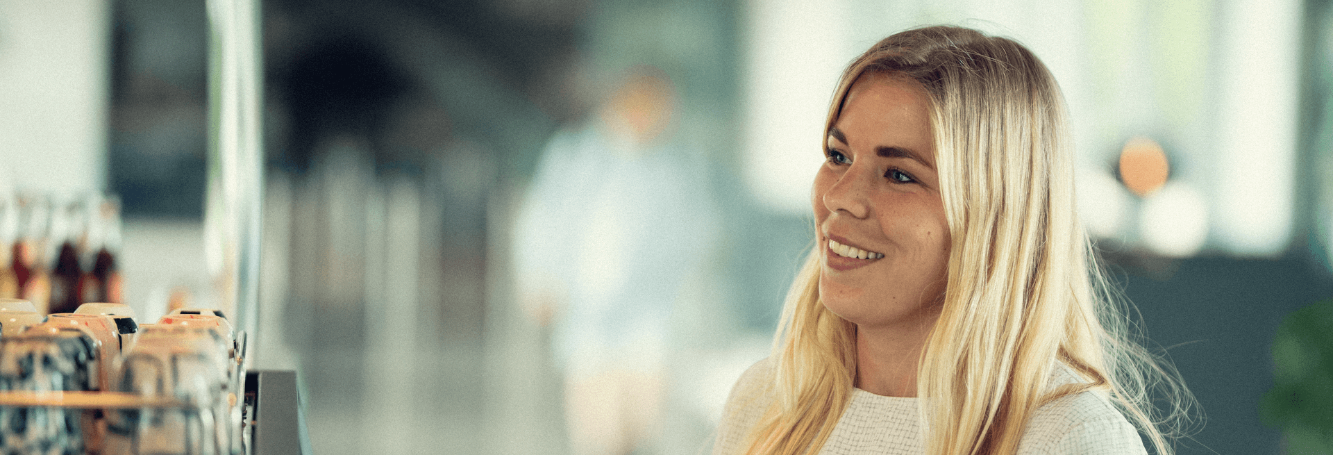 woman standing at what appears to be a counter, smiling and engaged in a friendly interaction.