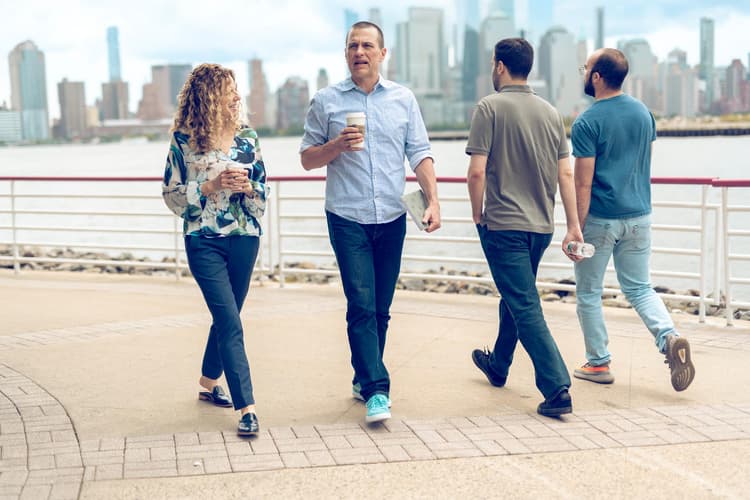 People walking with coffee next to river