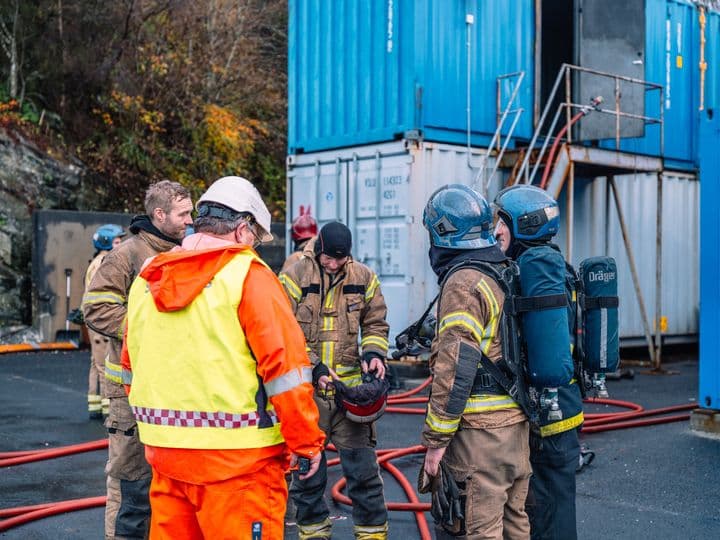 Emergency response trainees in firefighting gear receiving instructions during a fire safety training exercise, building skills for handling high-risk situations.